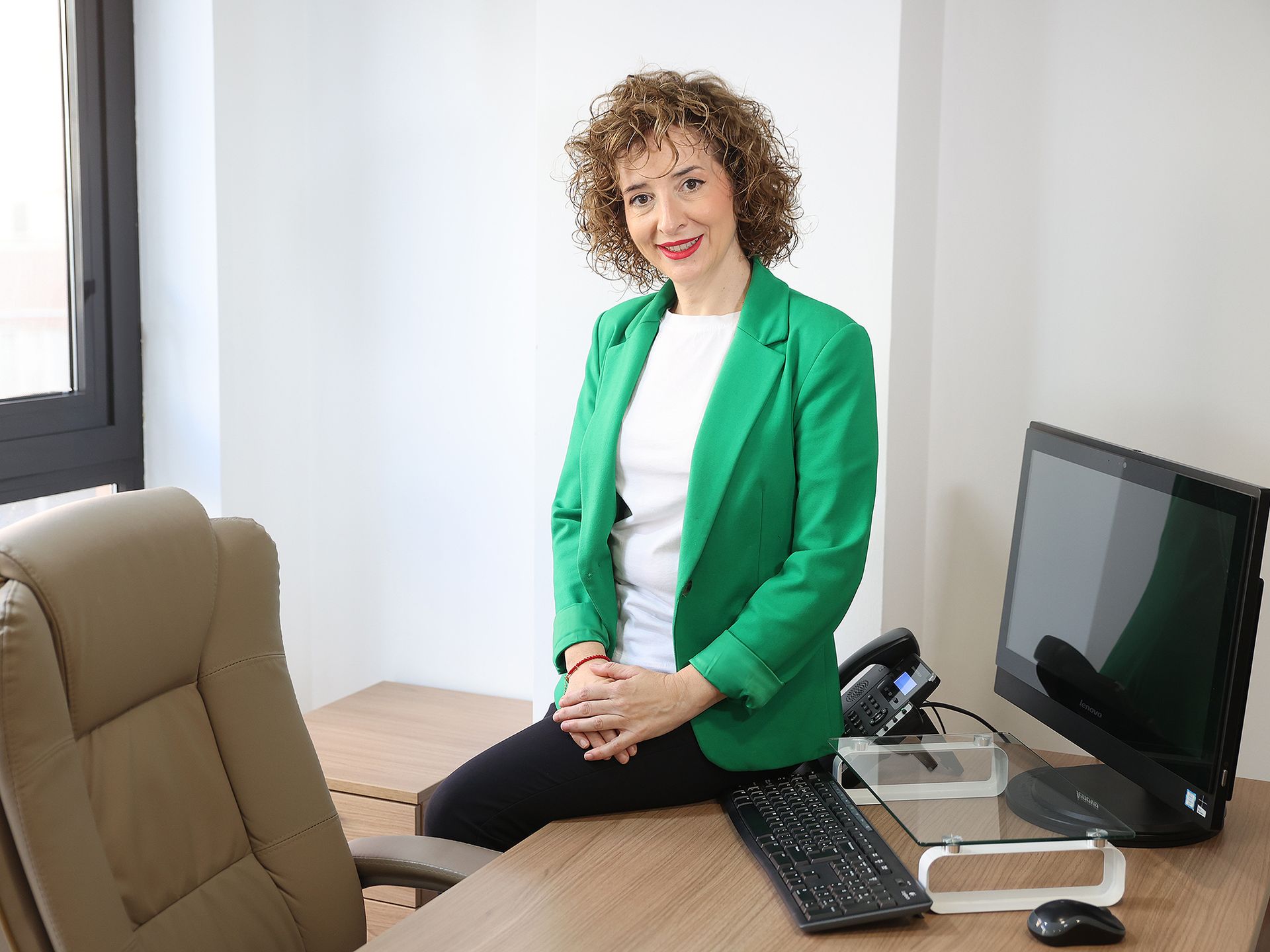 Una mujer con cabello rizado está sonriendo y vistiendo una blusa médica.