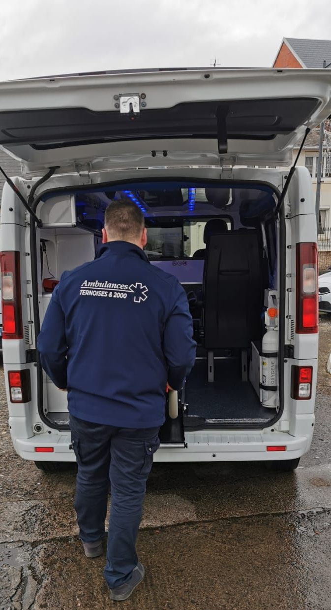 un ambulancier de dos range un brancard dans son ambulance.