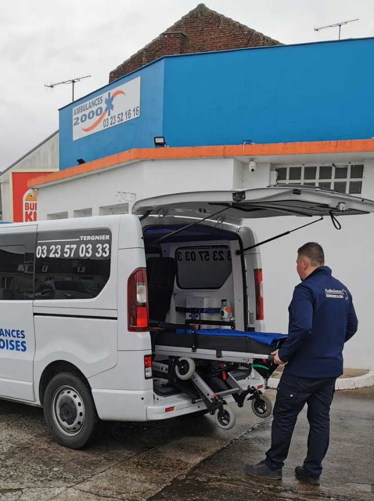 Un ambulancier remet un brancard dans son ambulance.