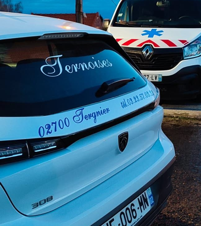 Des mains agrippant un volant noir, au volant d'une voiture dont le fond urbain est flou.