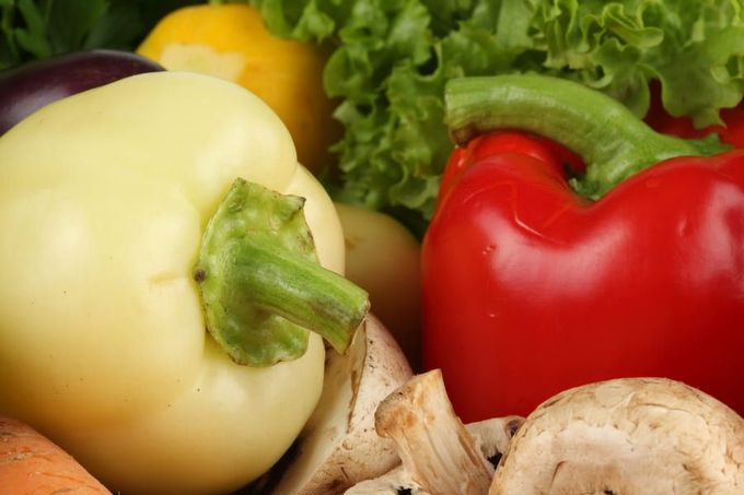 Un primer plano de una variedad de verduras, incluidos pimientos, champiñones, zanahorias y lechuga.