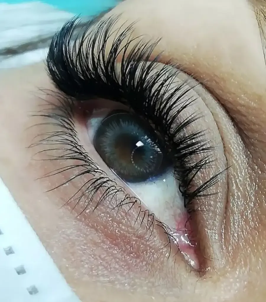 Primer plano de un ojo con extensiones de pestañas largas y oscuras y una lágrima.