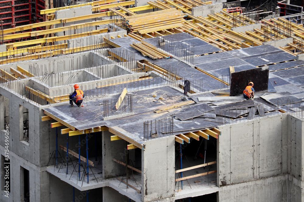 Baustelle mit Betonrahmen, Bewehrungsstahl und zwei Arbeitern auf der Dachplatte