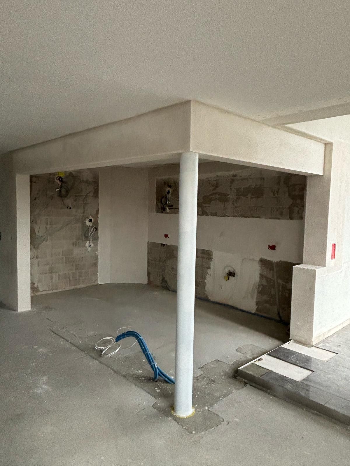 Ein Baugerüst neben einem beigen Gebäude mit einem blauen Schild an der Spitze.