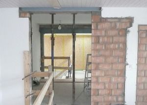 Teilweise renoviertes Zimmer mit freiliegender Ziegelwand und Gerüst um eine Fensteröffnung