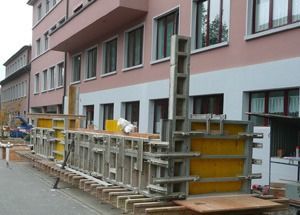 Baustellenabsperrungen und Baugeräte säumten den Gehweg neben einem rosafarbenen Gebäude, das gerade renoviert wurde.