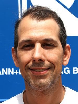 Nahaufnahme eines lächelnden Mannes vor blauem Hintergrund mit weissem Text