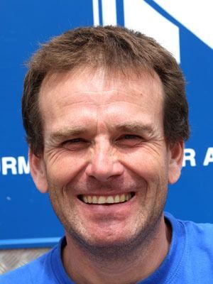 Lächelnder Mann in einem blauen Hemd vor blauem Hintergrund