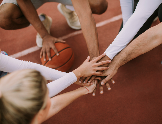 Un gruppo di persone unisce le mani su un campo da basket.