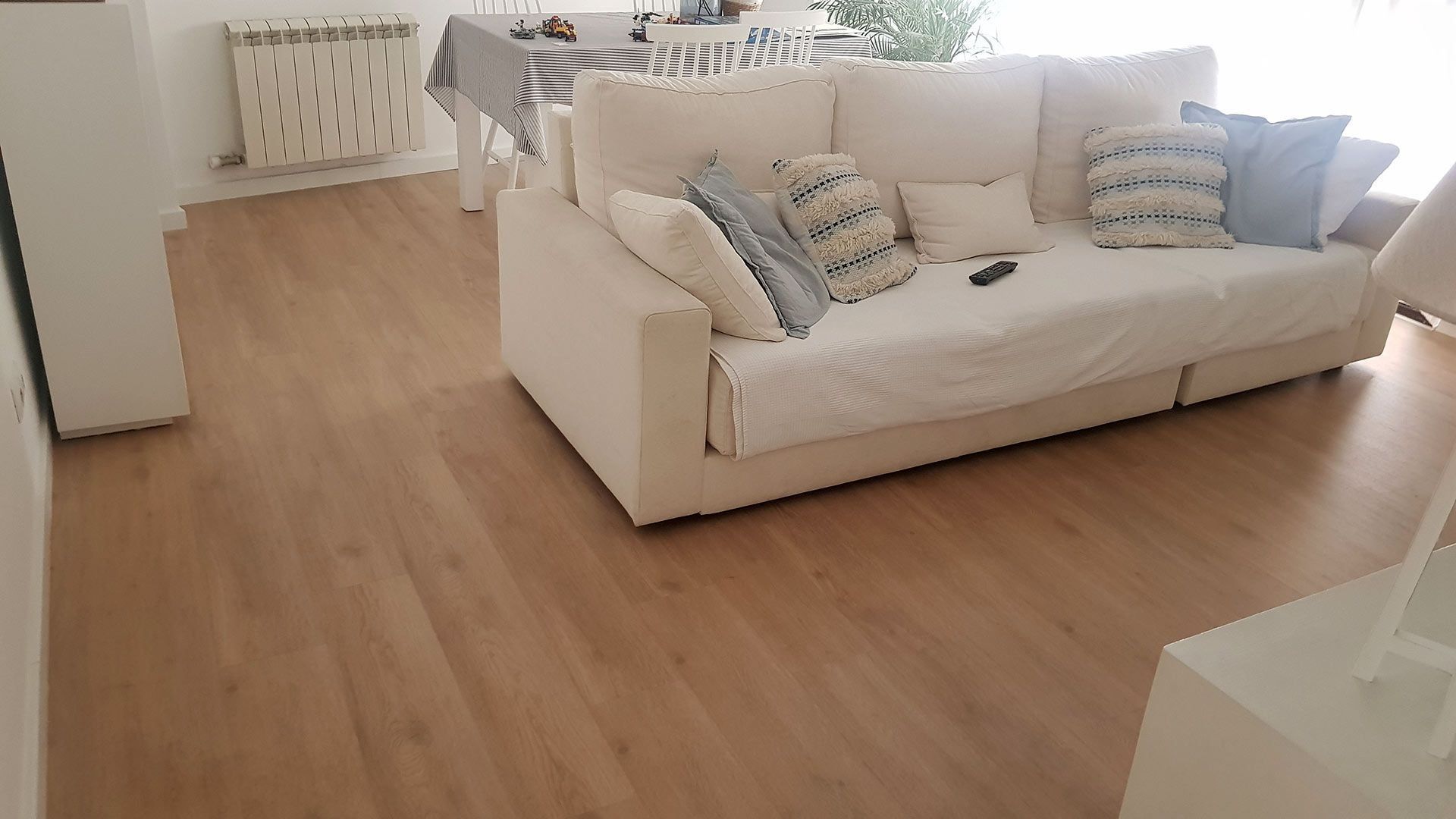 Sala de estar luminosa con sofá color crema, suelo de madera y luz natural suave.