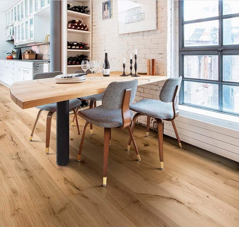 Comedor moderno con mesa de madera, sillas grises y grandes ventanales en una habitación luminosa.