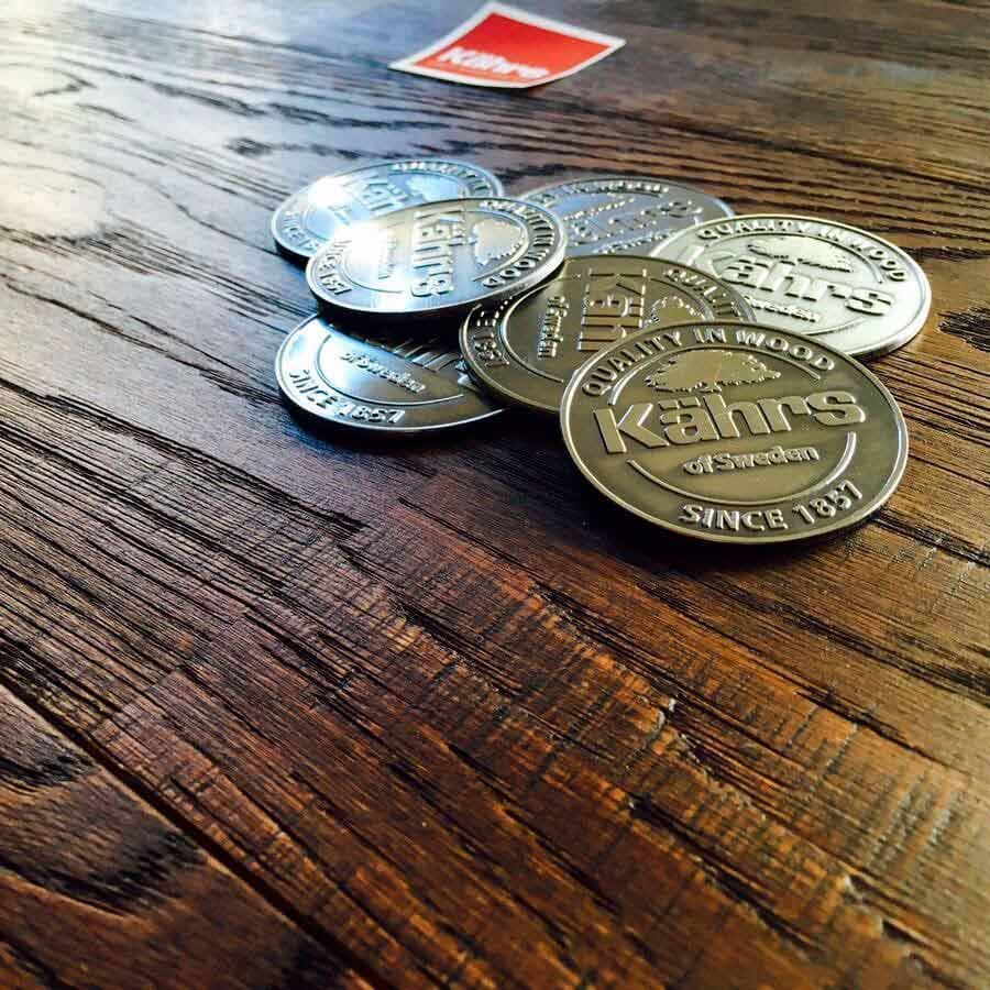 Monedas de oro esparcidas sobre una mesa de madera, con una pequeña tarjeta roja al fondo.
