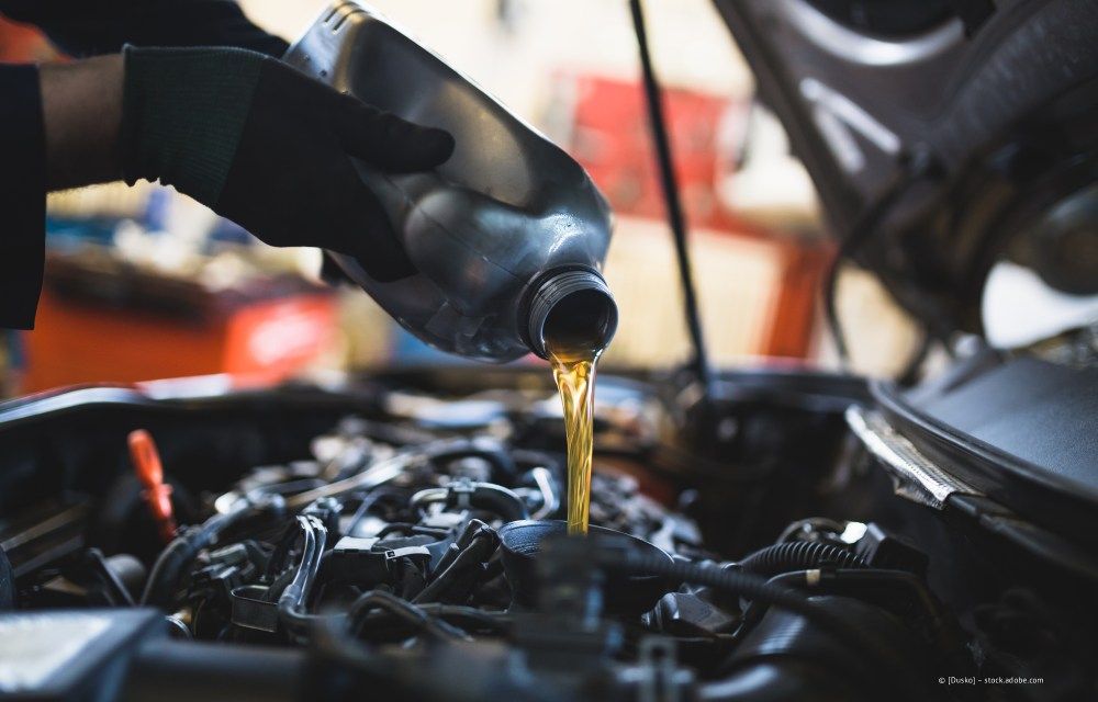 Ein Mechaniker füllt in einer Garage Motoröl in einen Motor.