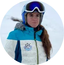Una mujer que lleva casco y gafas protectoras está parada en la nieve.