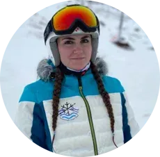 Una mujer que lleva casco y gafas protectoras está parada en la nieve.