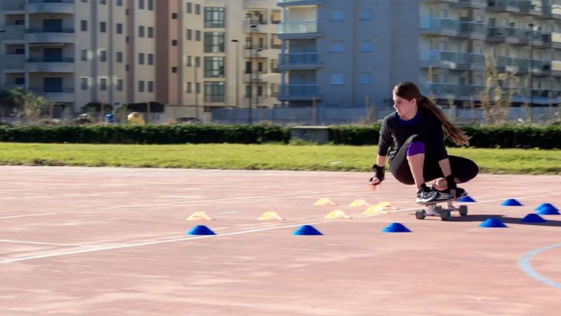 Una mujer está arrodillada sobre una patineta en una pista.