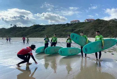 Un grupo de personas están de pie en una playa sosteniendo tablas de surf.
