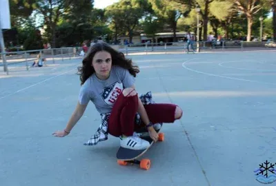 Una niña está montando una patineta sobre una superficie de concreto.