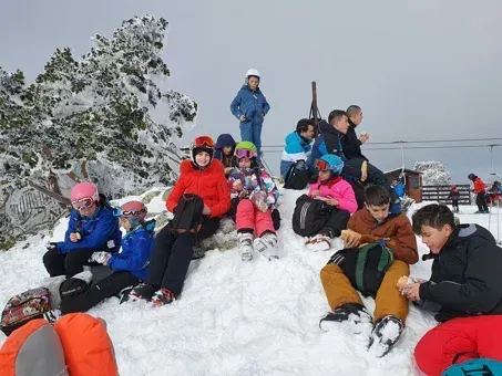 Un grupo de personas sentadas en la cima de una colina cubierta de nieve.