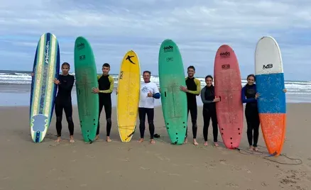 Un grupo de personas de pie en una playa sosteniendo tablas de surf.