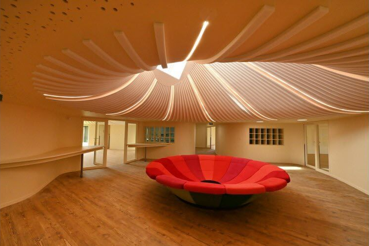 Intérieur d'une pièce en construction avec plafond en bois, murs en briques, fenêtres et câblage exposé.