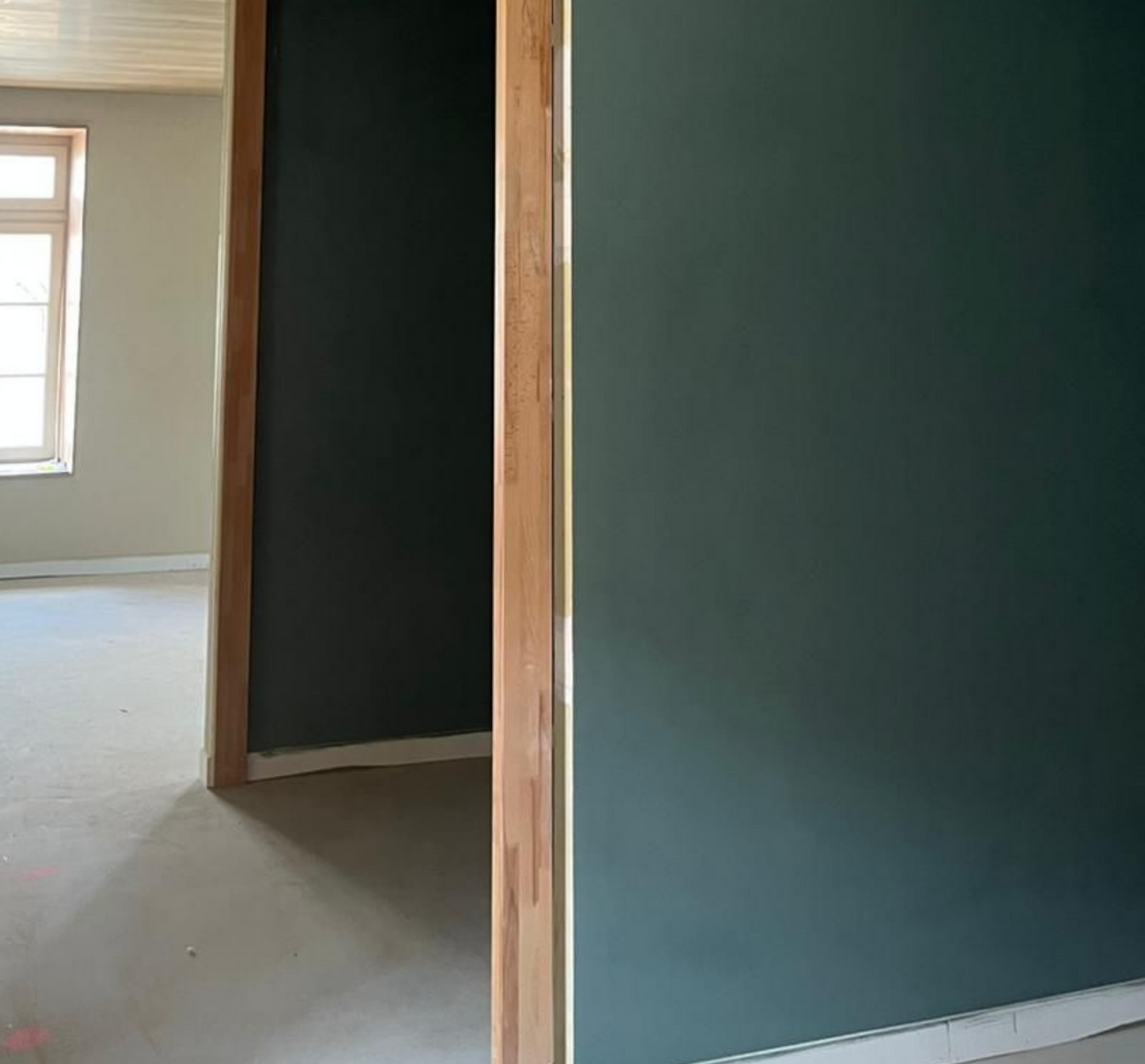 Cadres de portes en bois menant à des pièces aux murs vert foncé et clair.