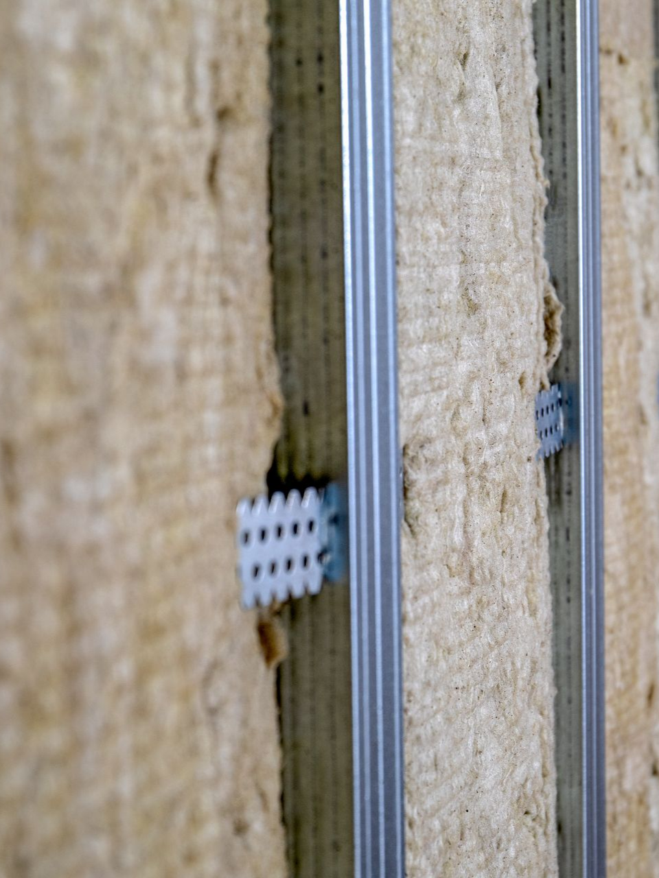 Isolation maintenue en place par des clips en plastique et des goujons métalliques, détail de construction.