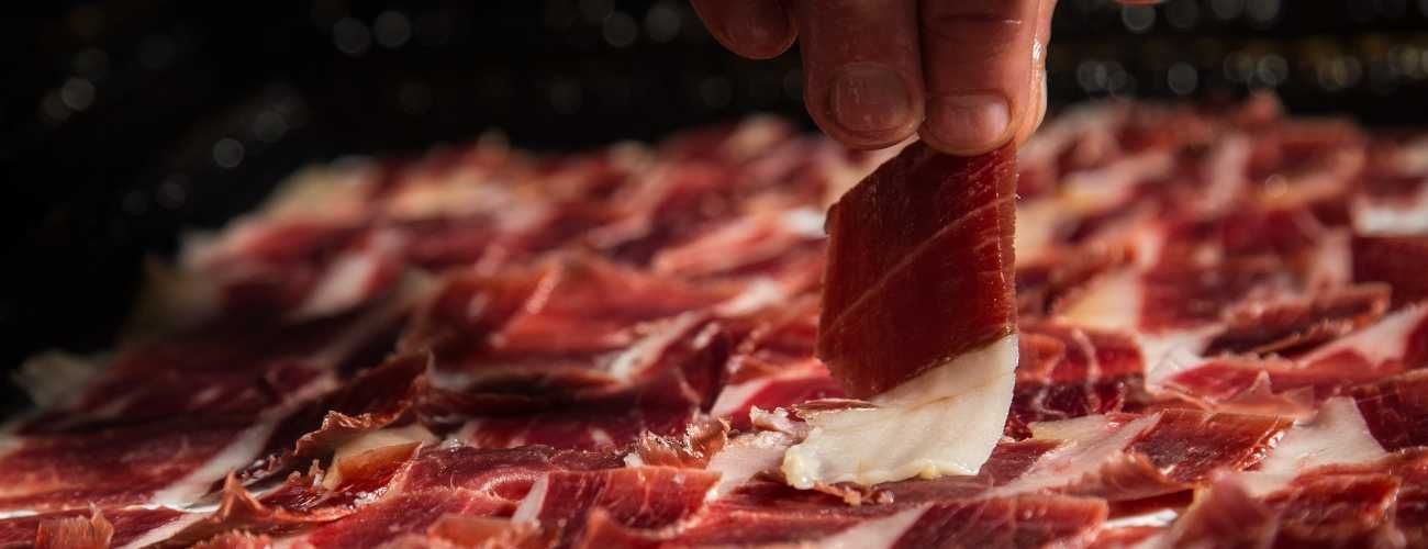 Una persona sostiene un trozo de carne sobre una pila de carne.