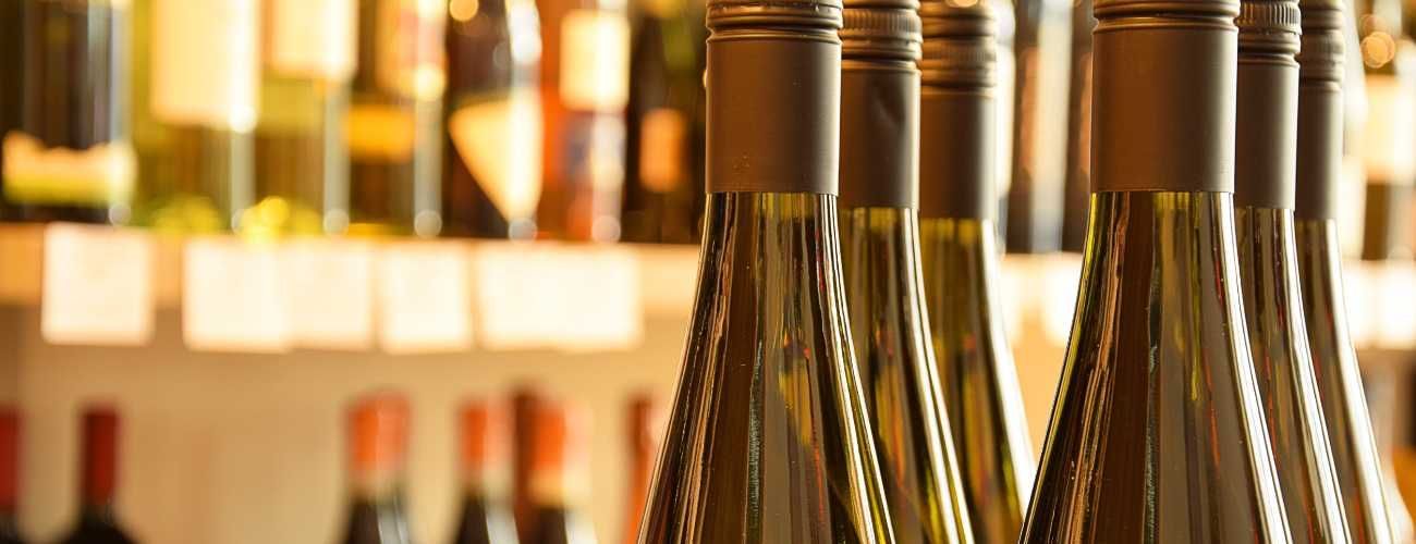 Una fila de botellas de vino colocadas una encima de otra en un estante.