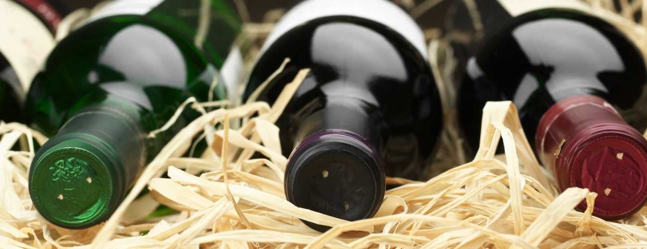 Tres botellas de vino están sobre una pila de heno.