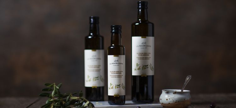 Tres botellas de aceite de oliva están sobre una mesa.