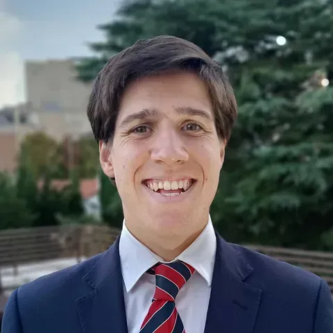 Un hombre con traje y corbata sonríe a la cámara.