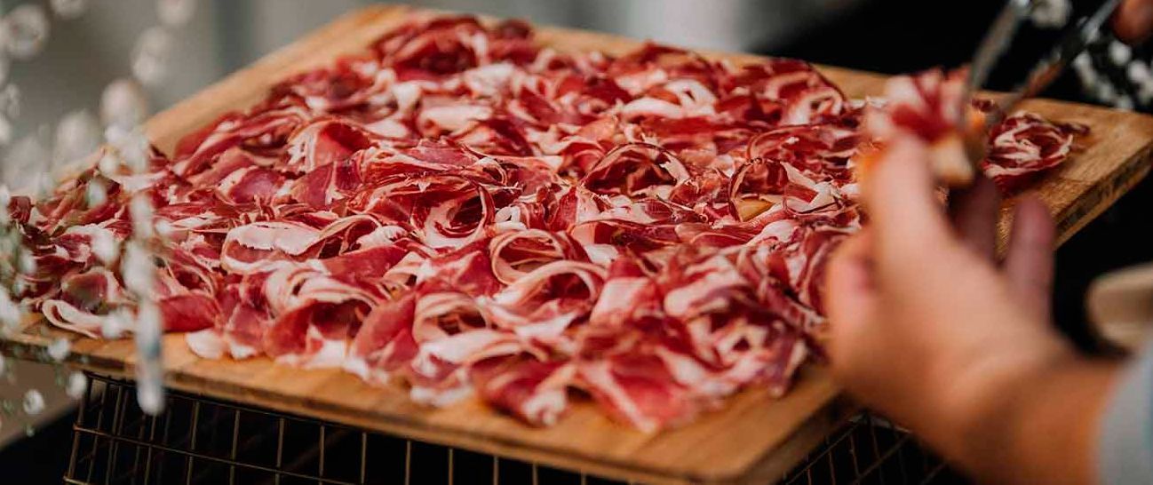 Una persona está cortando un trozo de carne en una tabla de cortar.