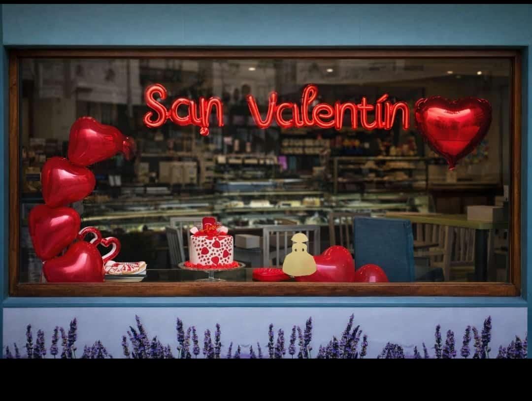 Escaparate de panadería de San Valentín con globos en forma de corazón y cartel de San Valentín.