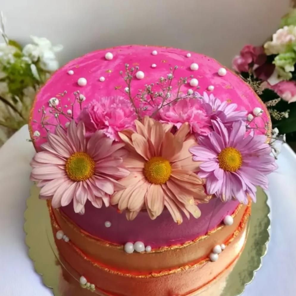 Pastel rosa y naranja decorado con flores y perlas comestibles.