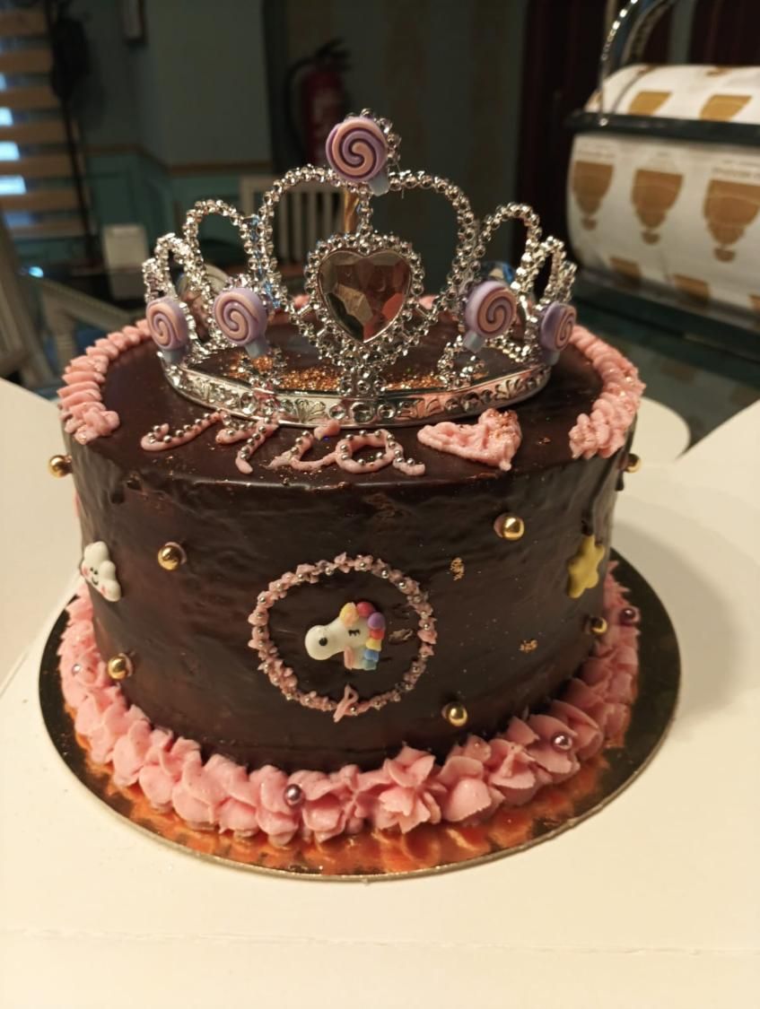 Pastel de chocolate con tiara de princesa, glaseado rosa y detalles dorados.