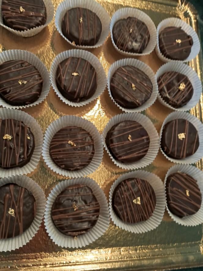 Galletas cubiertas de chocolate en vasos de papel blanco sobre una bandeja dorada