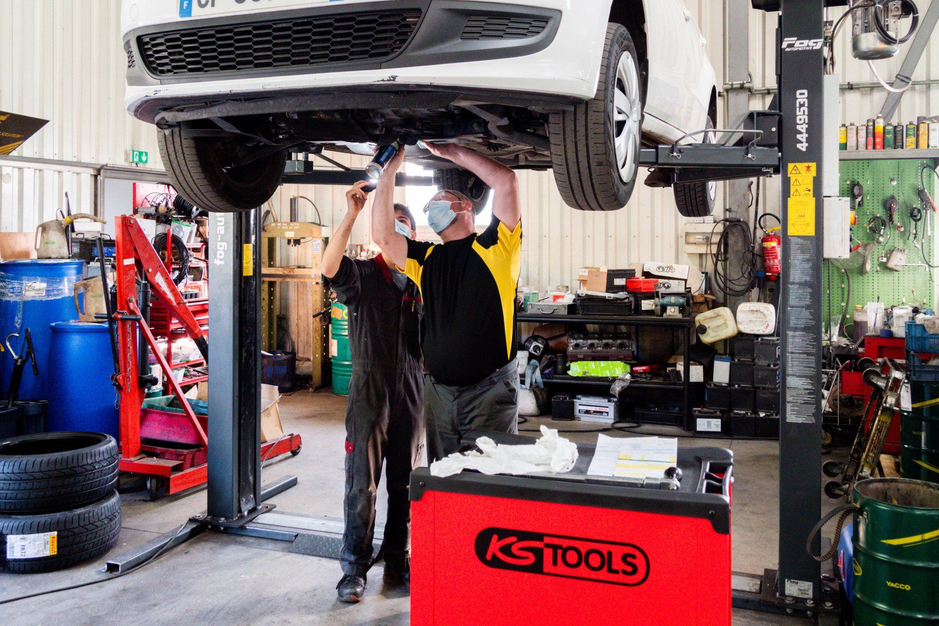 Mécaniciens regardant le dessous d'une voiture