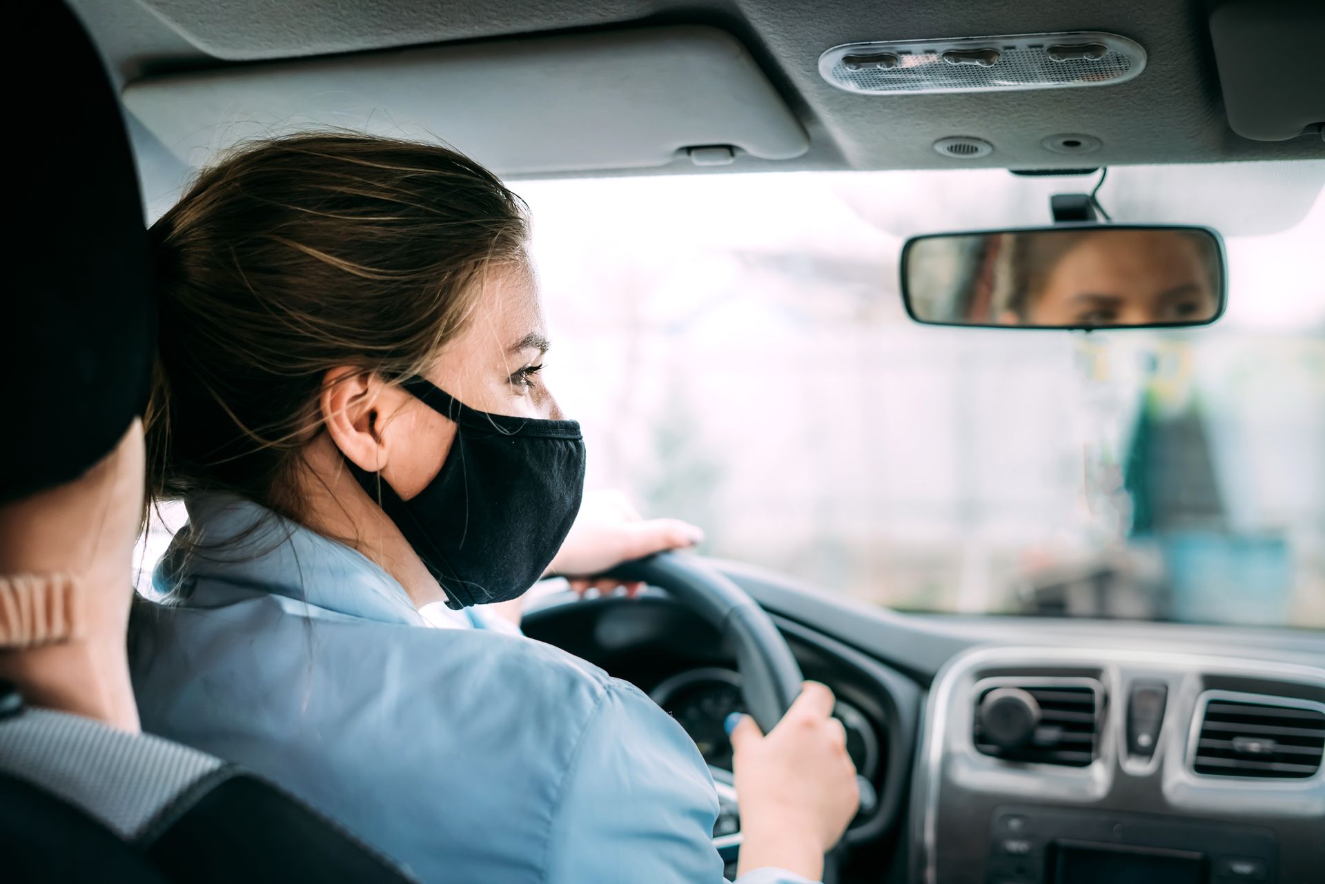 Une femme avec un masque au volant d'un véhicule
