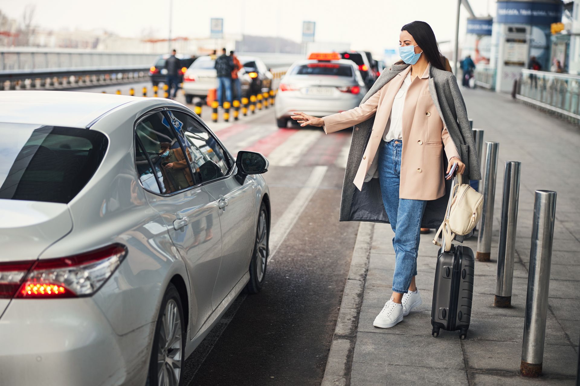 Une femme portant un masque tend le bras vers une voiture