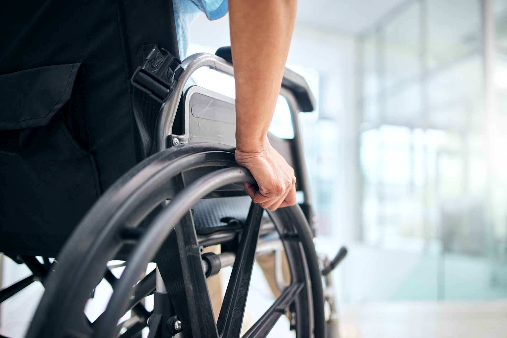 Une main sur la roue d'un fauteuil roulant
