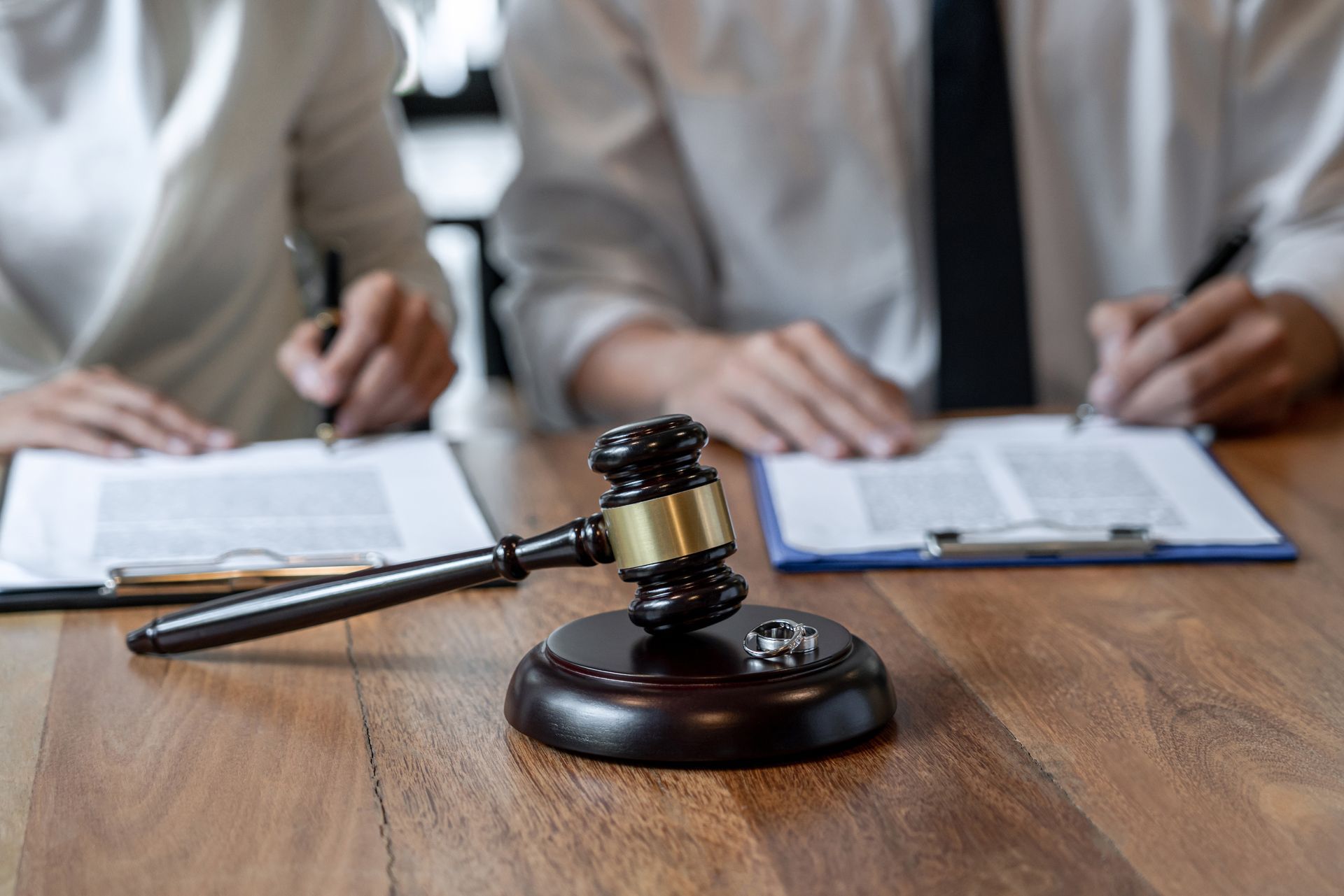 Marteau de justice avec deux personnes signant des papiers en arrière-plan