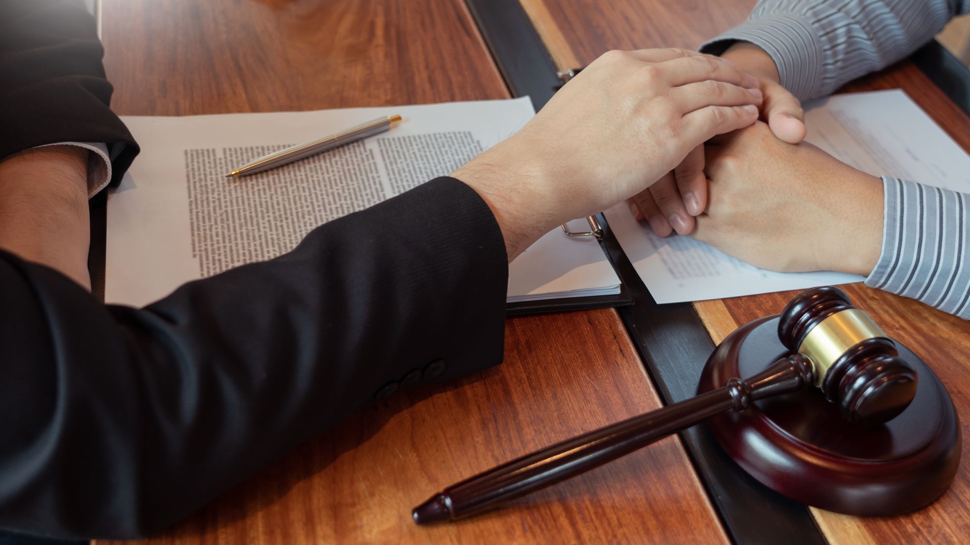 Marteau de la justice avec une personne posant sa main sur les mains d'une autre personne