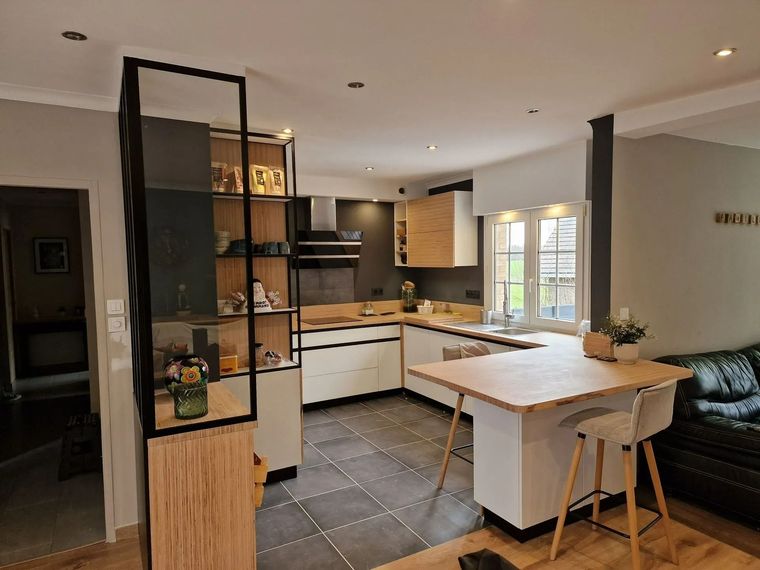 Cuisine moderne avec placards blancs, sol en carrelage noir, îlot en bois et étagères près d'une fenêtre.