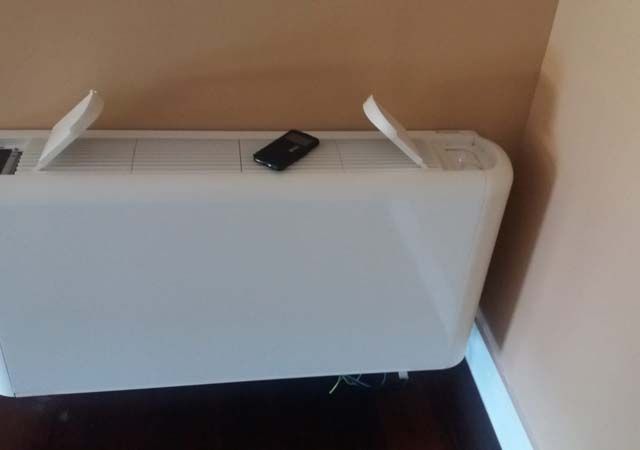 Un calentador blanco está sobre un piso de madera al lado de una pared.