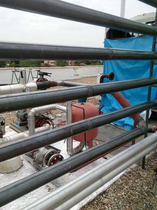 Un montón de tuberías están detrás de una valla con una lona azul al fondo.