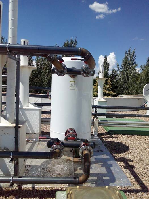 Un gran tanque blanco con una válvula está rodeado de tuberías.