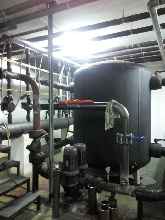 Un gran tanque negro está rodeado de tuberías en una habitación.