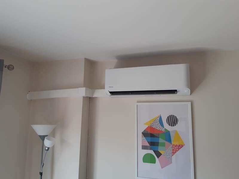 Una habitación con un cuadro en la pared y un aire acondicionado montado en la pared.