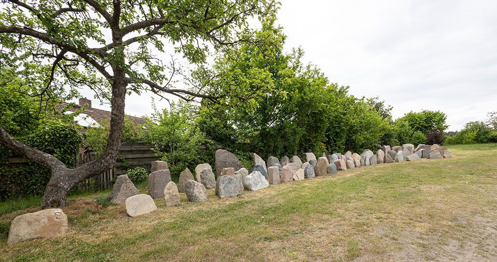 Eine Reihe von Felsen auf einer Wiese mit Bäumen im Hintergrund.